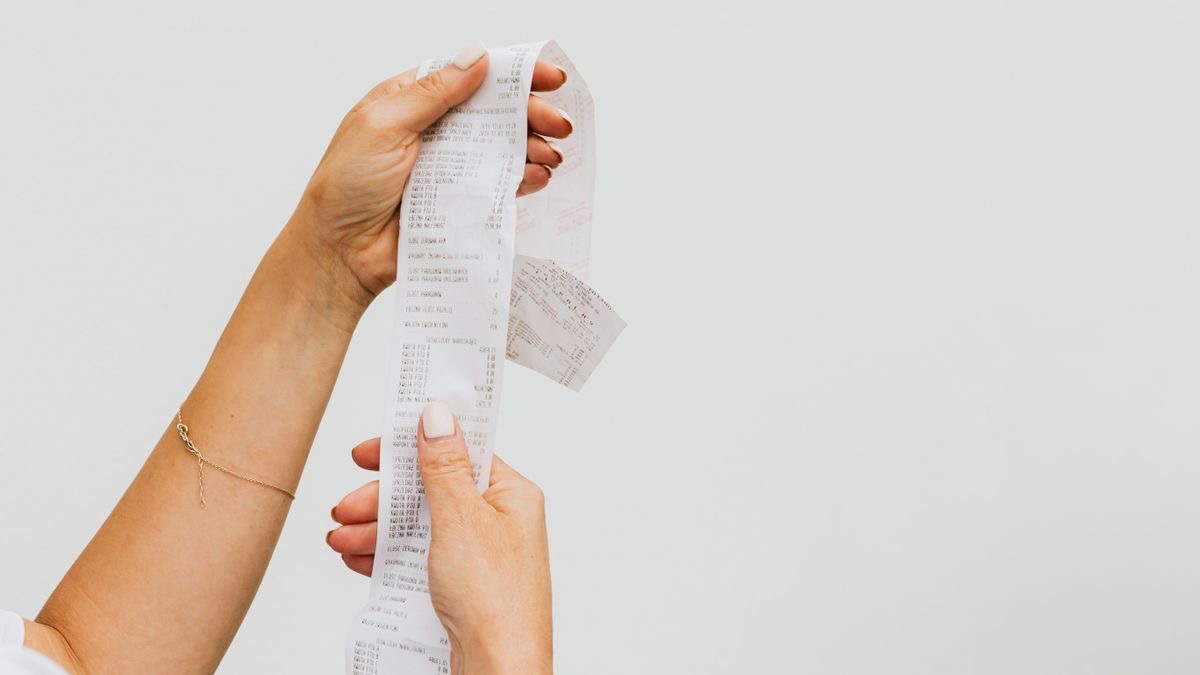 Hands holding a long itemised paper receipt, representing the Apify line items that appear on an invoice beyond the headline actor price