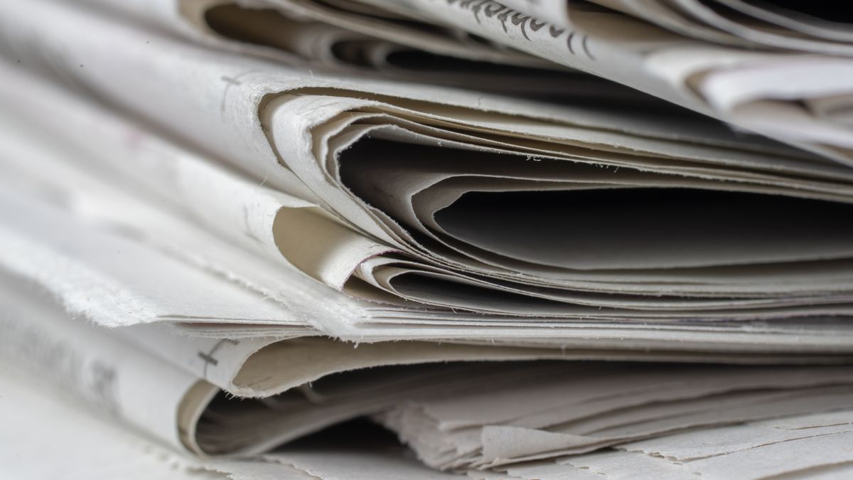 A close-up stack of folded newspapers, representing a Google News API for media monitoring