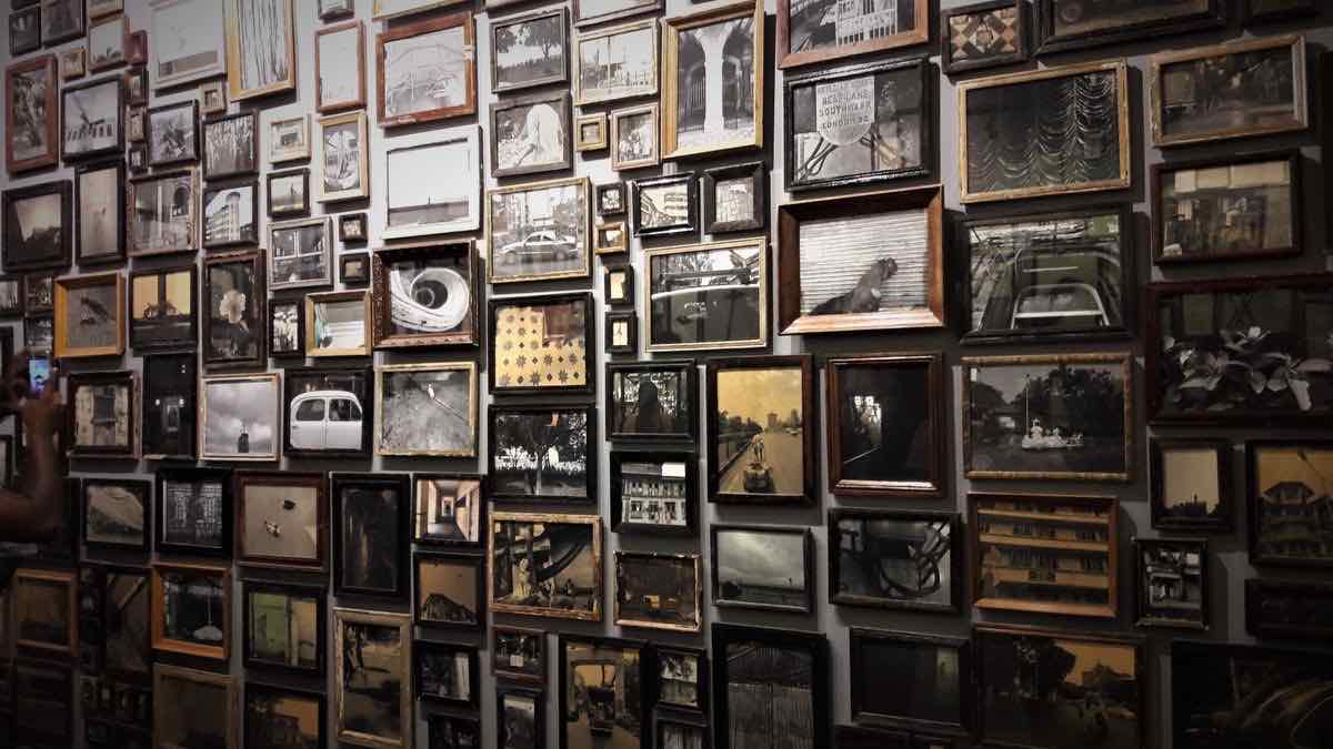 A gallery wall packed edge to edge with framed pictures of every size, in mismatched frames