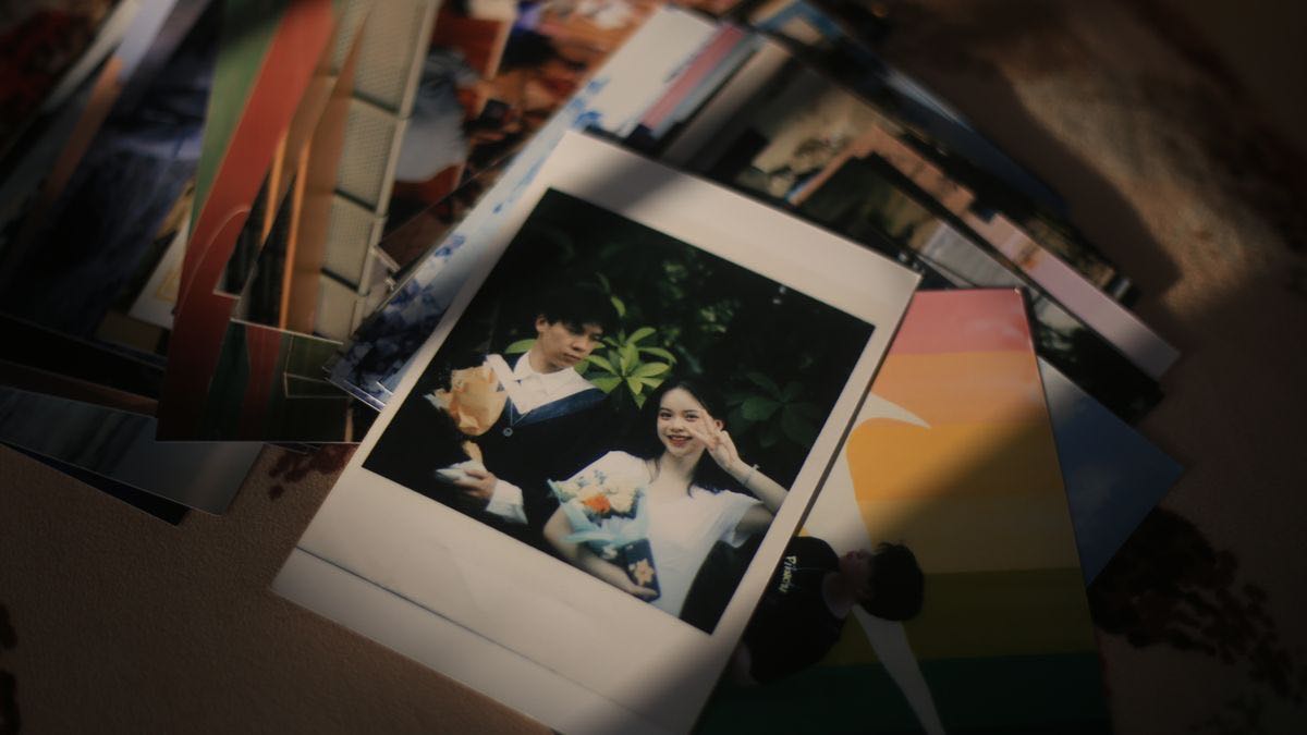 A spill of instant-camera prints across a table with one graduation photograph of a couple in focus on top of the pile