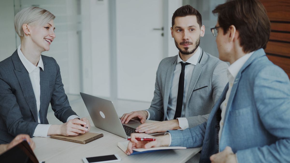 Three professionals reviewing options together at a table with a laptop, deciding which LinkedIn data API fits their use case