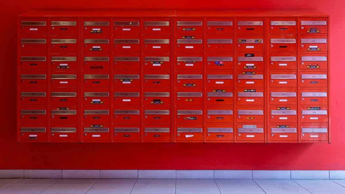 A wall of dozens of identical red letterboxes, each one an interchangeable address