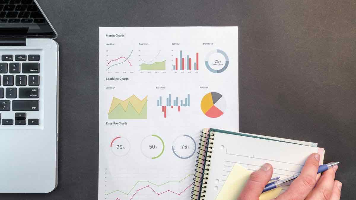 A notebook beside a laptop showing charts, the way you review the cost and coverage of a TikTok data source