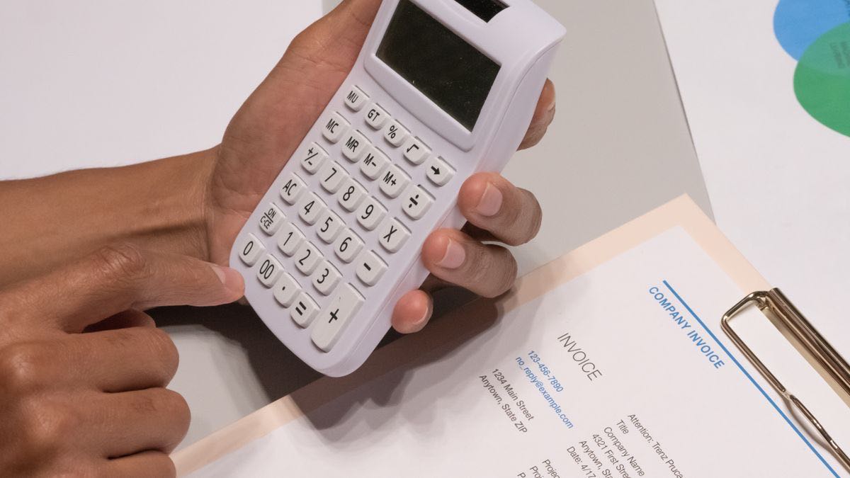 Hands using a calculator next to a company invoice, working out the per-record cost of a LinkedIn data plan