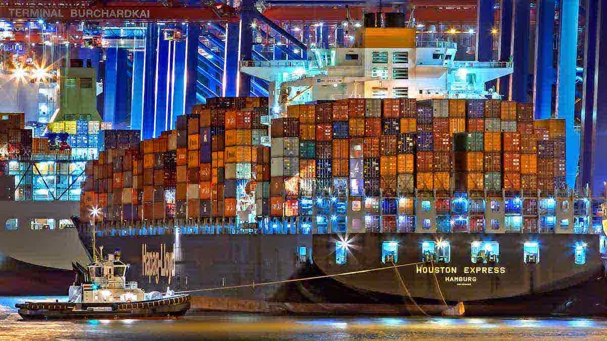 Container ship being loaded under floodlights at night — the overnight batch window in physical form