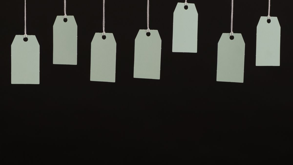 Seven blank paper price tags hanging on strings against a black background, representing prices a vendor does not publish