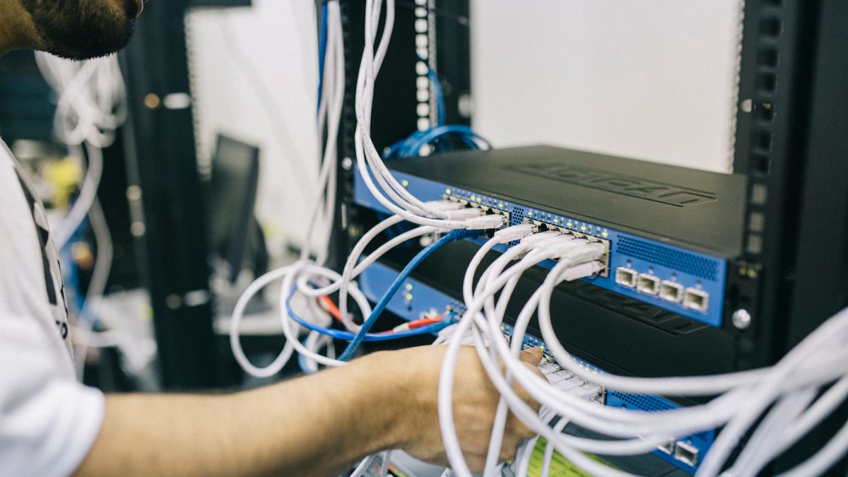 A technician plugging Ethernet cables into a network switch, representing scraping traffic over a metered proxy