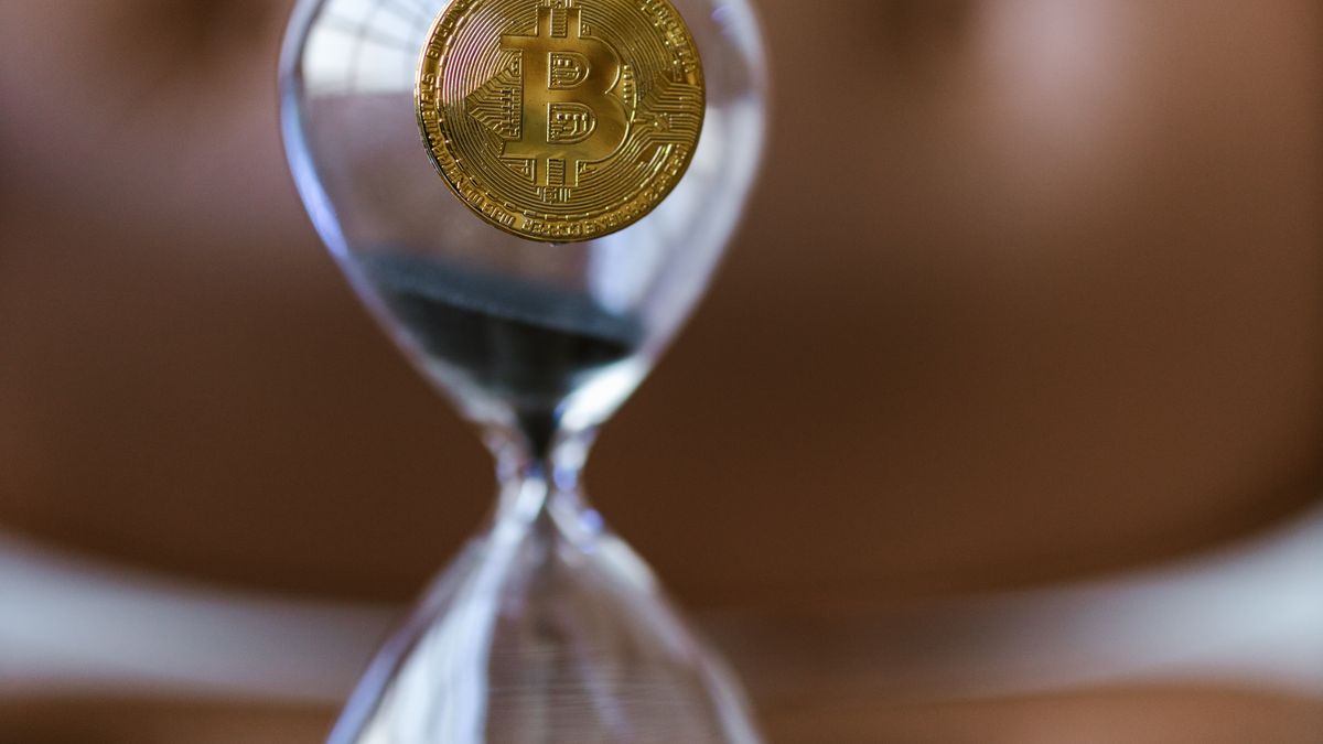 A gold coin balanced on an hourglass, illustrating SERP API credits running out of time