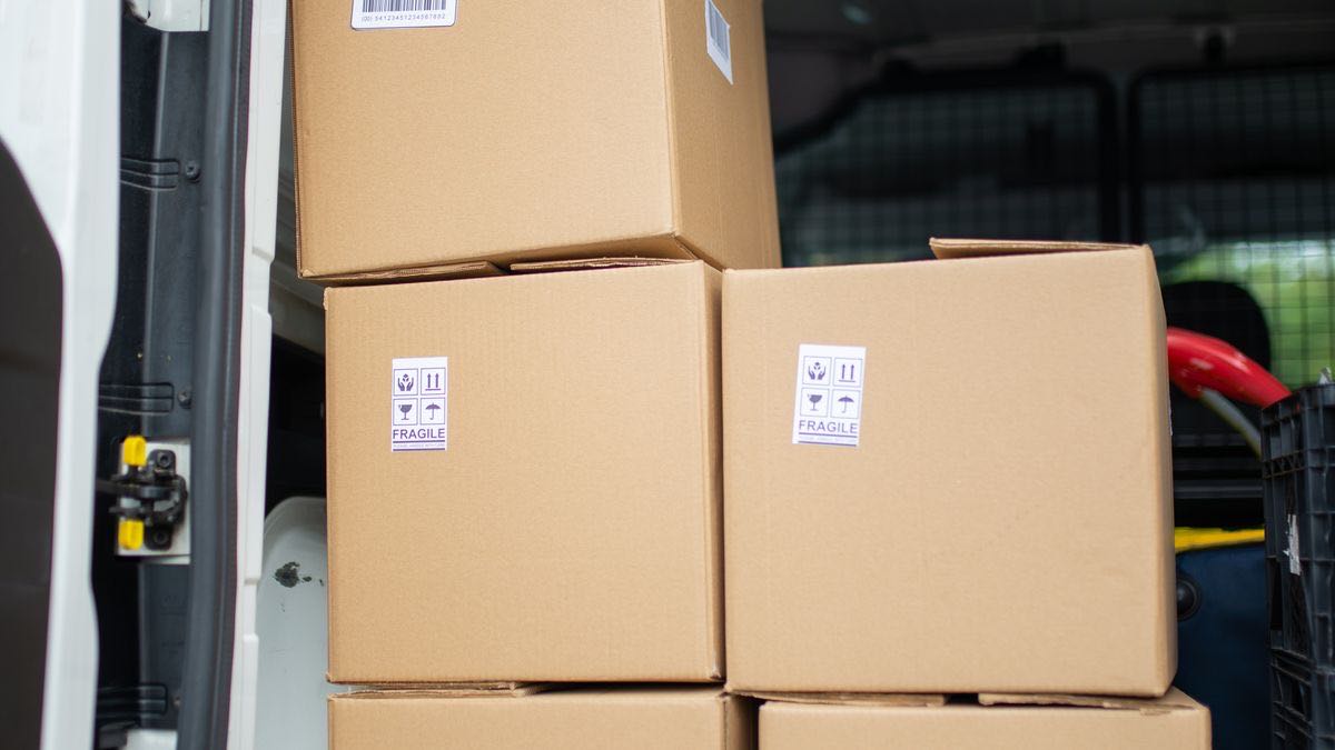 Cardboard boxes with fragile stickers stacked in the back of a delivery van