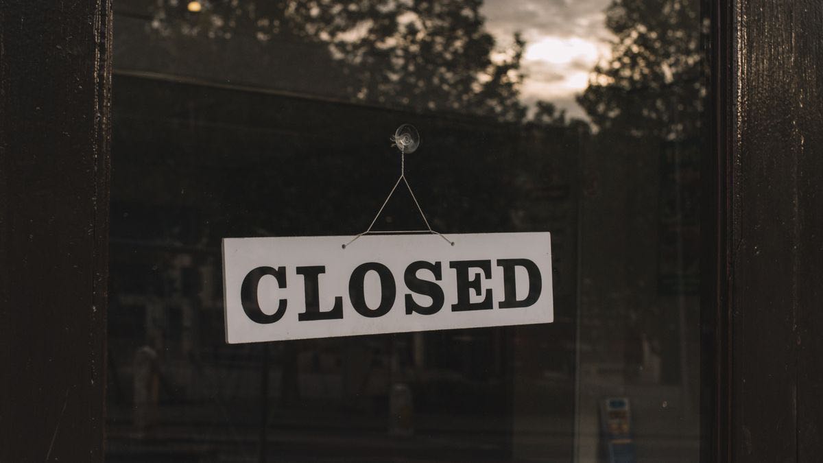 A white CLOSED sign hanging in the glass door of a dark shopfront, standing for the retired free Bing Search API