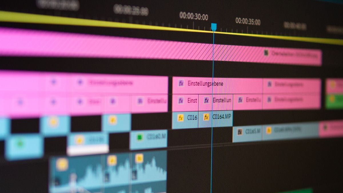 Close-up of a video editing timeline on a monitor with colored clip tracks and a playhead