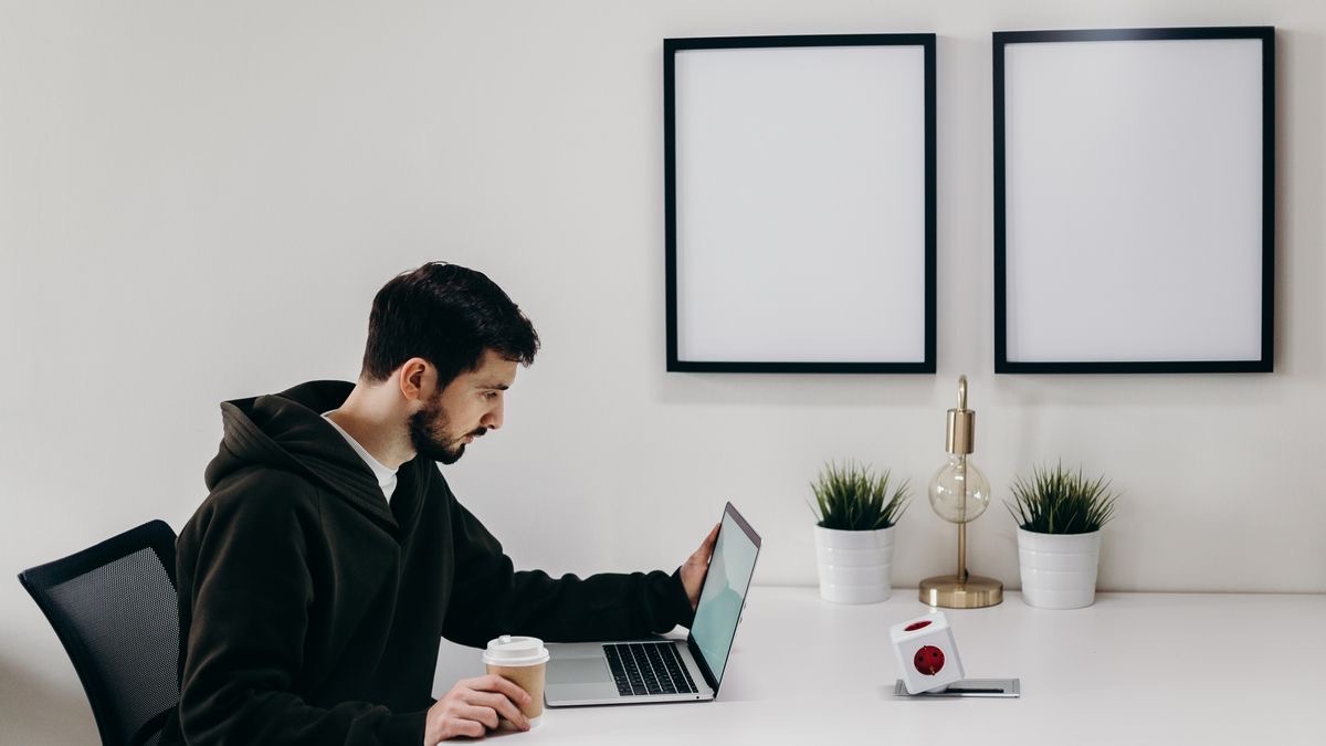 A developer working at a laptop below two empty picture frames — pulling public LinkedIn profile data, some of which comes back blank