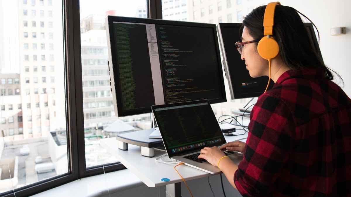 A developer coding at a dual-monitor setup, fetching public profile data through the API