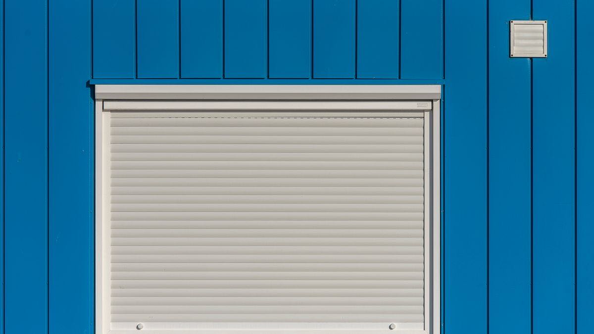 A white roller shutter closed over a window in a bright blue wall, representing Google closing search to plain HTTP clients
