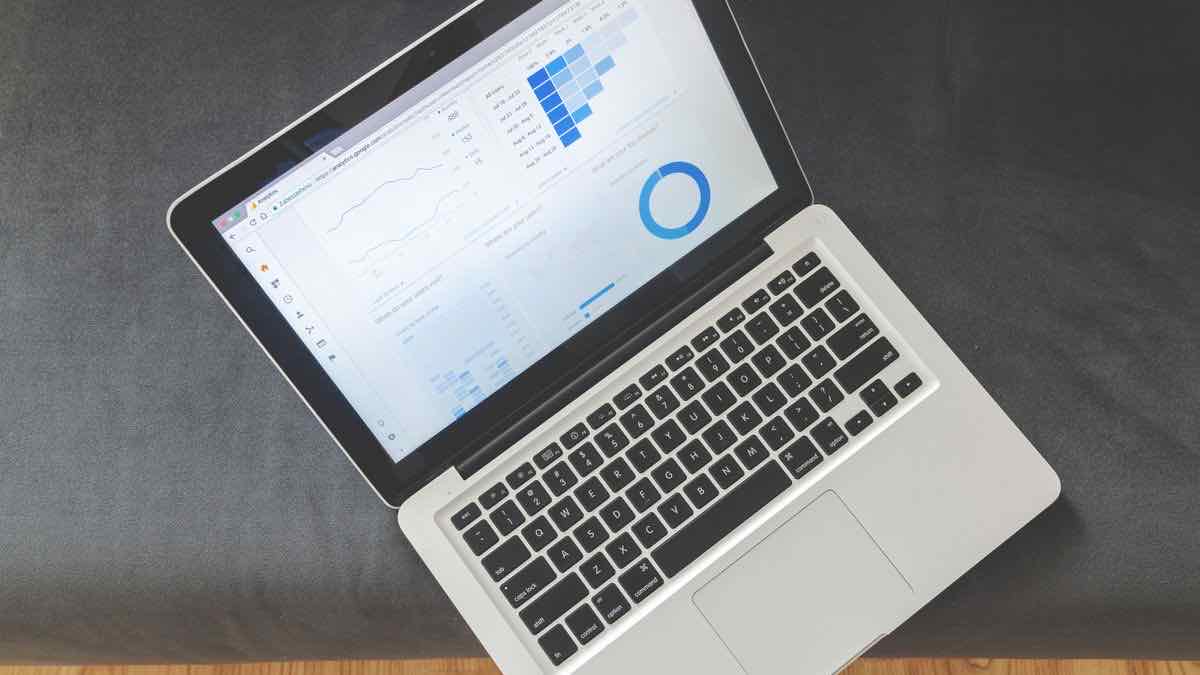 A laptop showing an analytics dashboard with a trend line, a bar chart and a donut chart