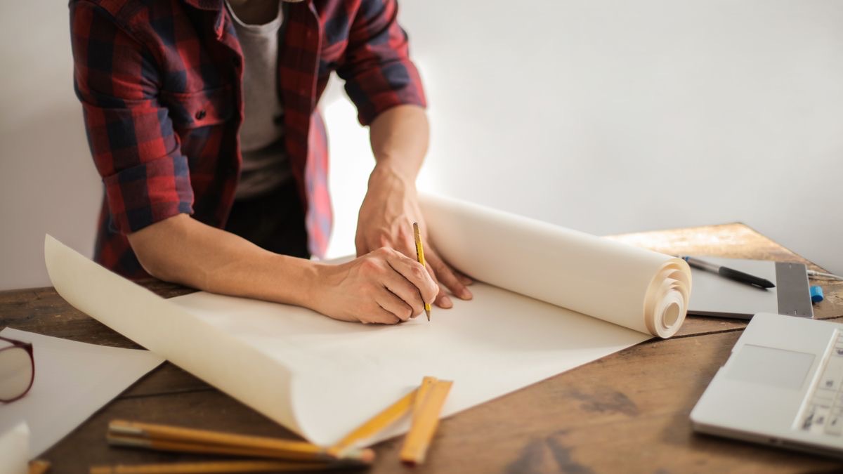 A person sketching a scoring model on paper at a workbench