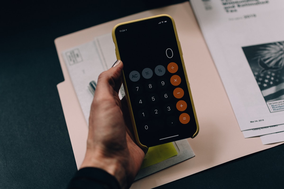 A hand holding a calculator over invoices and tax forms, representing a surprise AI grounding bill