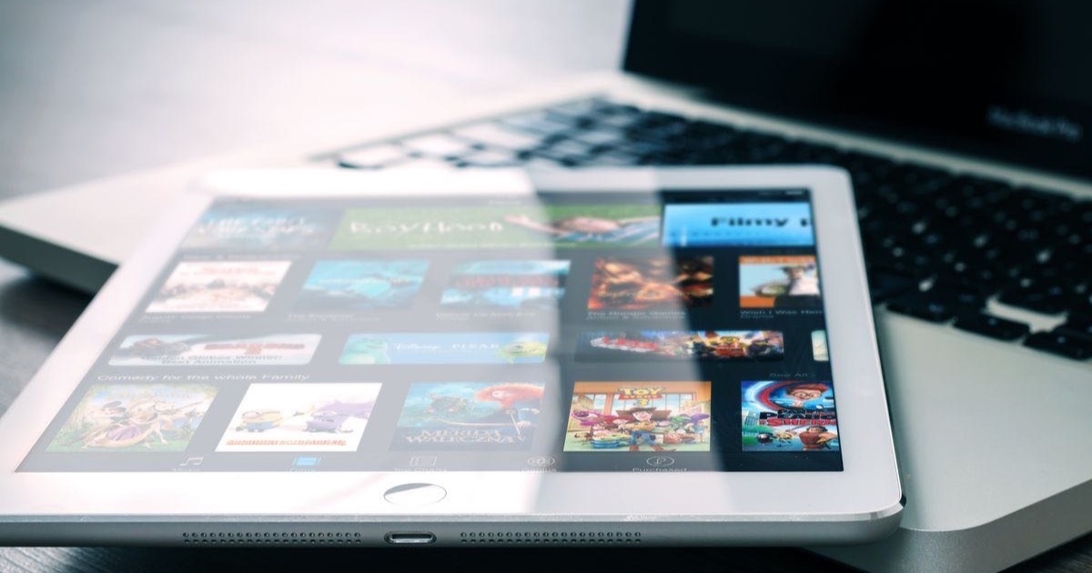 Tablet showing video thumbnails in front of a laptop