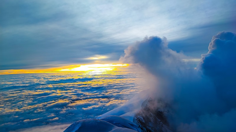 Sunrise breaking through clouds above a snow-capped mountain summit, evoking the climb to claim the top featured snippet position