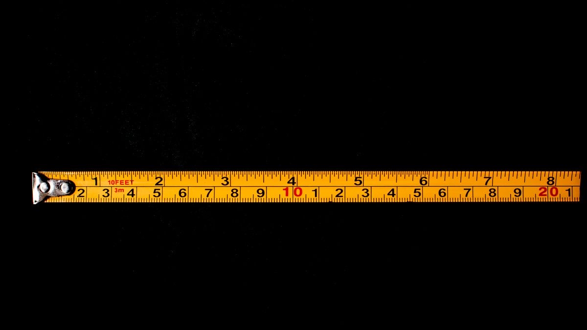 A yellow measuring tape extended on a black background, representing measuring rankings under fixed, controlled conditions