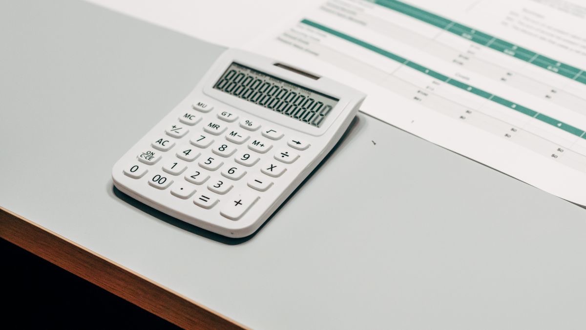 A calculator, printed spreadsheets and a pen on a desk, illustrating the per-1,000-record cost arithmetic behind a Reddit API comparison