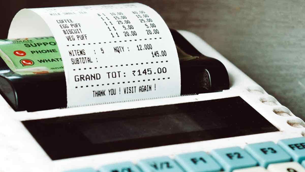 A till printing a long paper receipt with an itemised subtotal and grand total