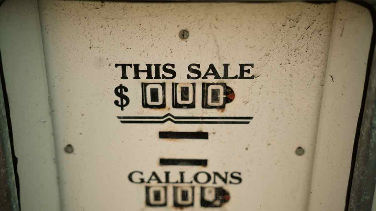 The mechanical counter on a weathered fuel pump reading THIS SALE in dollars and gallons, both dials blank