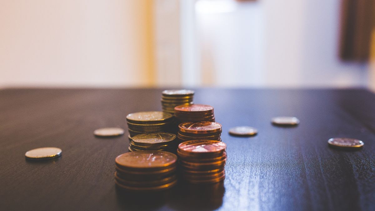 Stacks of coins on a table, representing ScraperAPI credits as a currency that buys fewer Google searches than expected