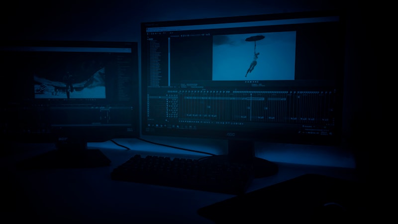 Dual dark monitors glowing blue in a low-lit workspace, the immersive setup an SEO analyst uses to watch live SERP dashboards