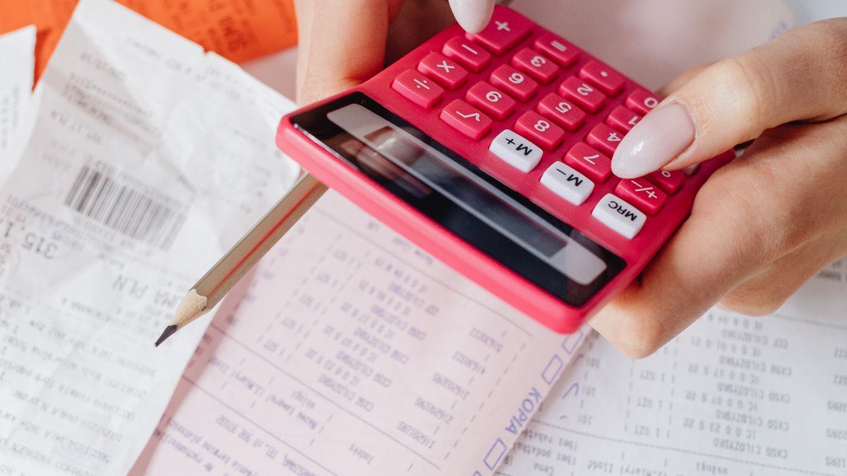 Hands working through a pile of receipts with a calculator, auditing itemized charges