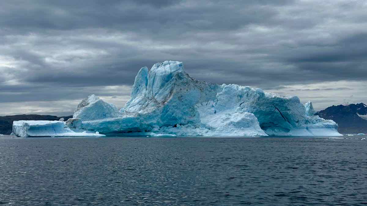 Iceberg with only part of its mass visible above dark water under a stormy sky