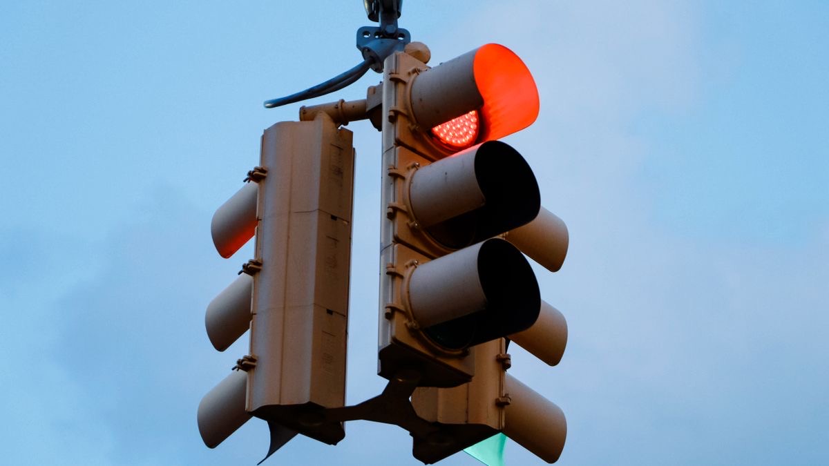 A traffic light showing red against a pale sky, representing a SERP API rate limit stopping requests