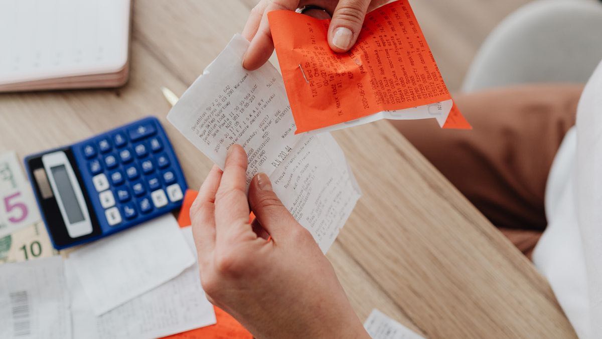 Person comparing several printed receipts at a desk with a calculator