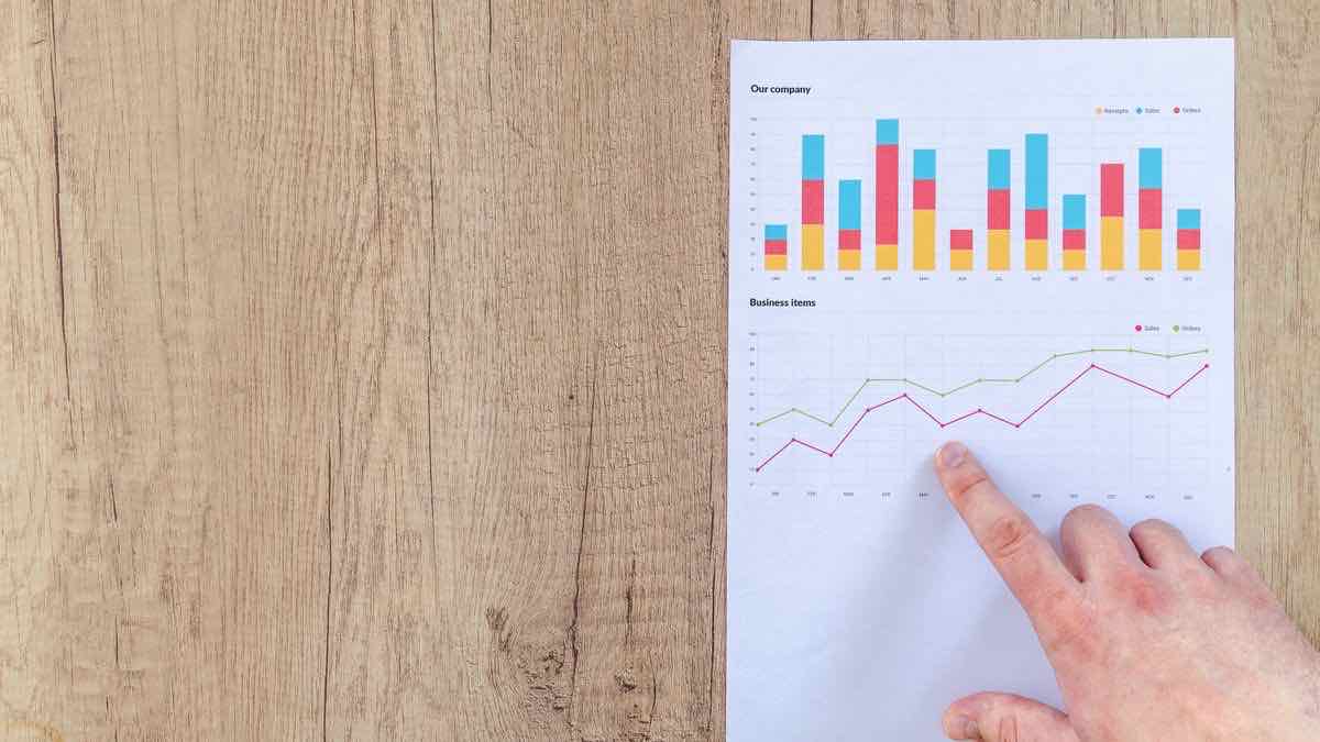 A hand pointing at printed bar and line charts comparing options on paper