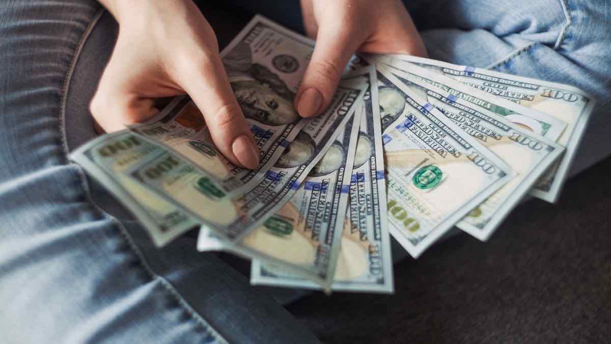 Hands fanning out a spread of hundred-dollar bills, representing what Serper credit packs actually cost