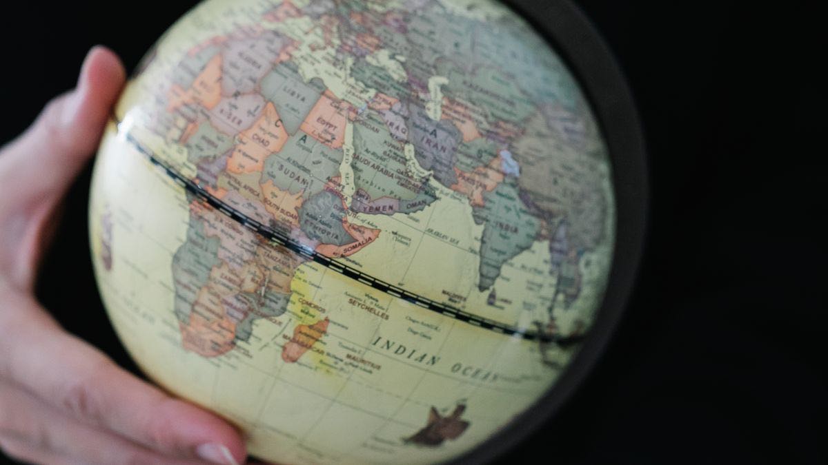 Hands holding a small desk globe against a black background