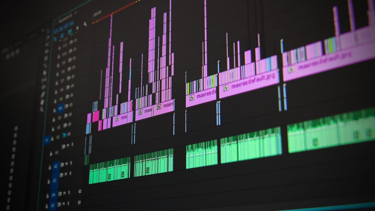 A video editing timeline with colored clips and audio tracks on a monitor